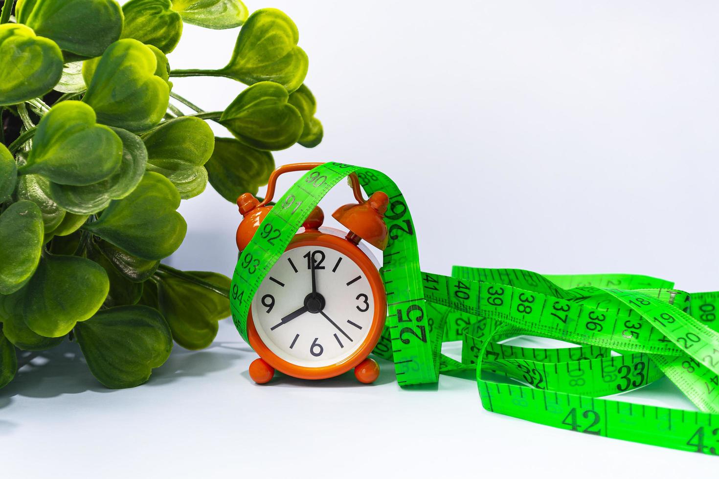 Measure tap with orange clock on white wooden background. Diet concept. photo