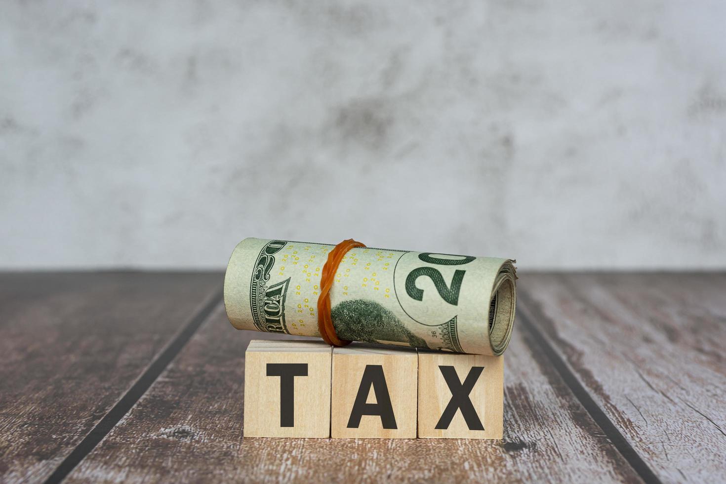 Tax text on wooden blocks and banknotes on wooden table. photo