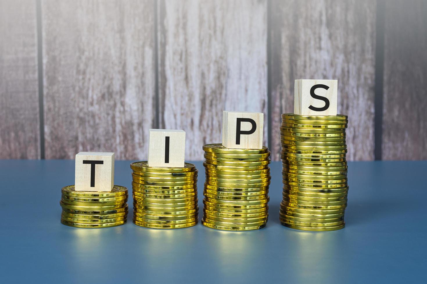 Tips text on wooden block cube on gold coins. Business concept. photo