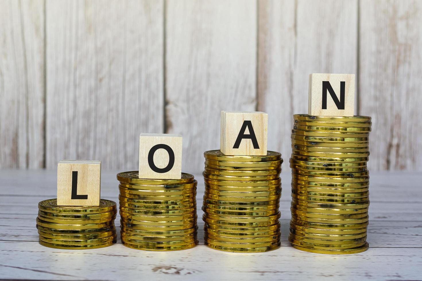 Loan text on wooden blocks with gold coins on a wooden table. Mortgage concept. photo