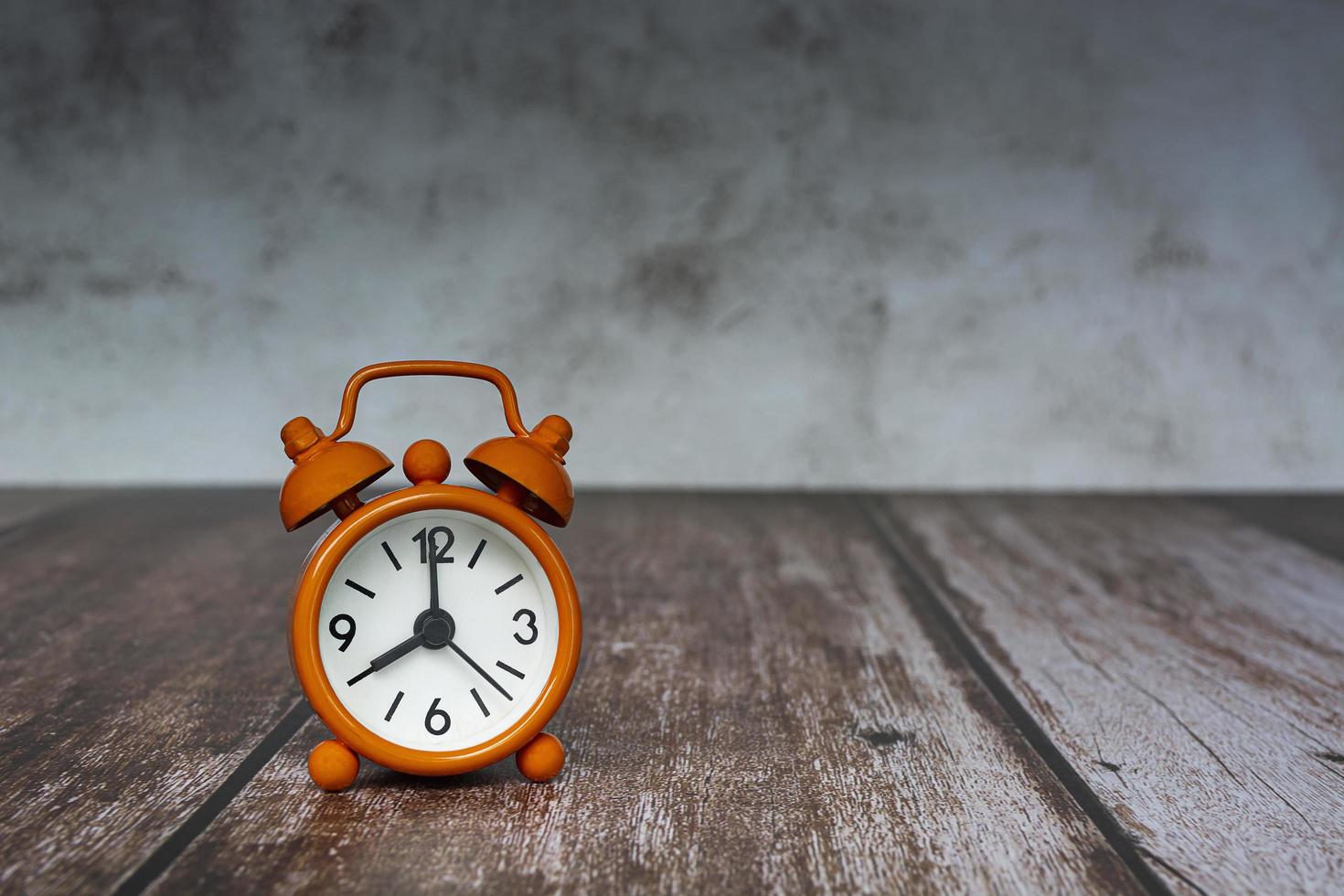 Orange alarm clock isolated on wooden desk. The clock set at 8 o'clock. photo