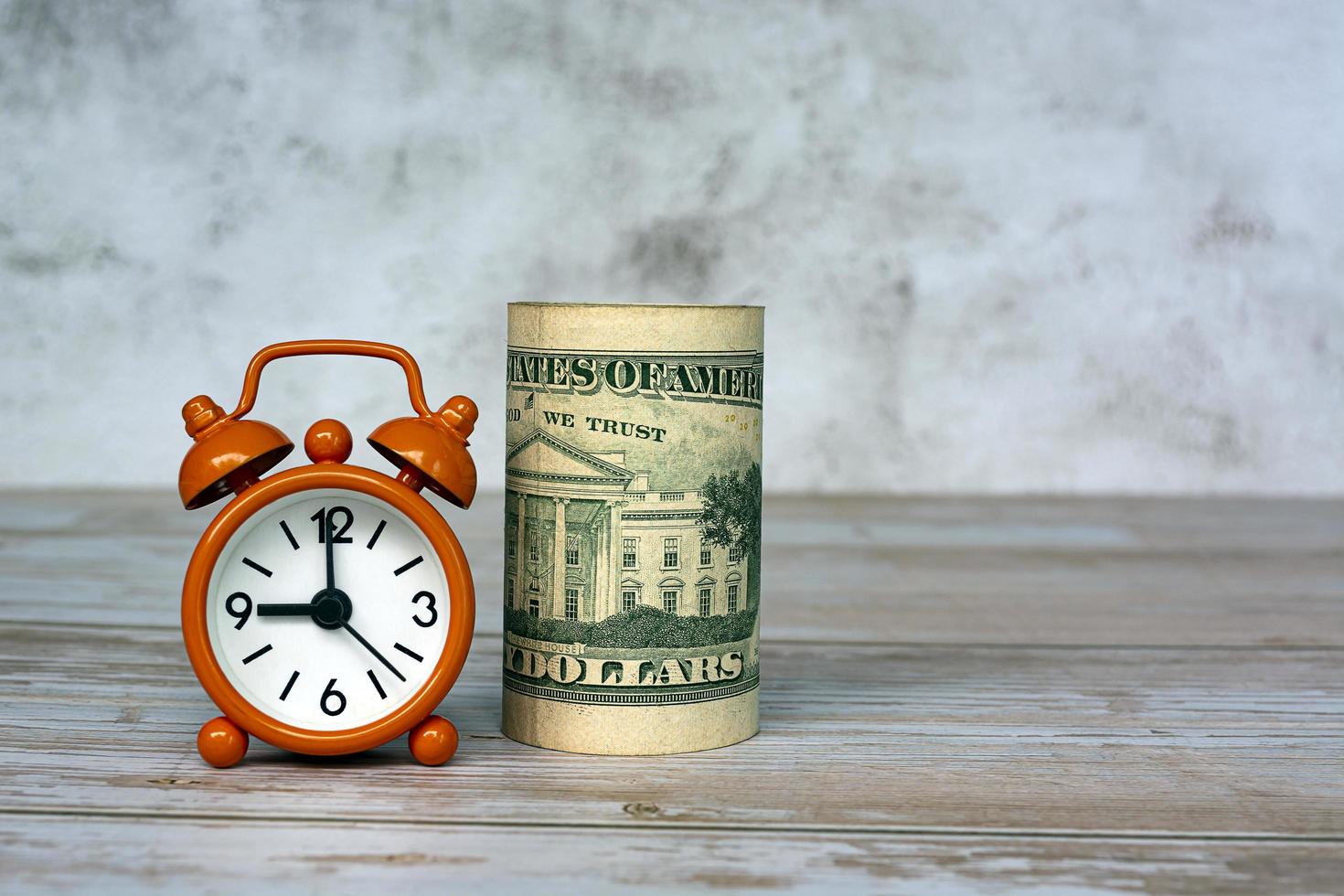 Alarm clock set at 9 o'clock with banknotes on table. Tax time concept. photo