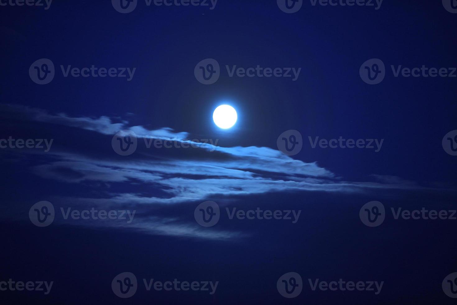 A beautiful big moon in a dark blue sky with clouds. photo
