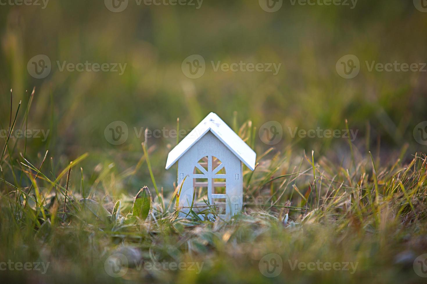 Figures of small white wooden houses on the grass close-up. The cottage is in a rural location and village, building, project, moving , mortgage, rent and purchase real estate. Copy space photo