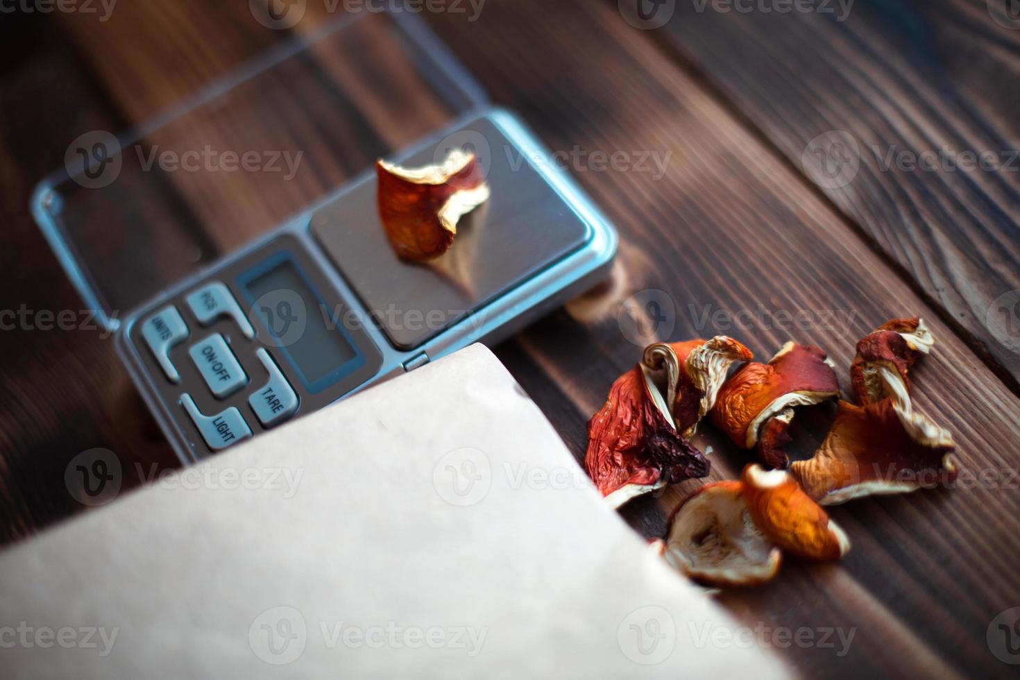 Dried pieces of mushroom fly agaric on table with scales. Measurement of microdose, microgram of psychedelic, therapeutic narcotic substance in poisonous Amanita muscaria. Microdosing, psychotropic photo