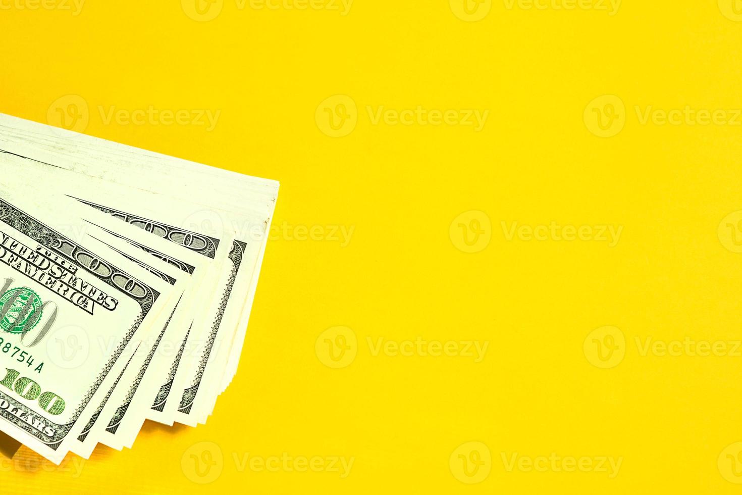 A stack of 100 bills on a yellow background. Concept Business, finance, investment, cash payment, savings, and wealth. Copy space photo