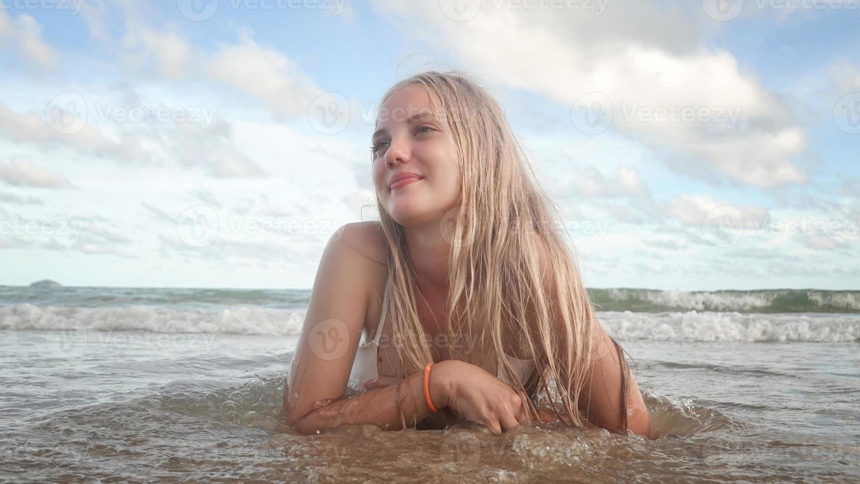 retrato de una hermosa mujer rubia disfruta de su verano en la playa. foto