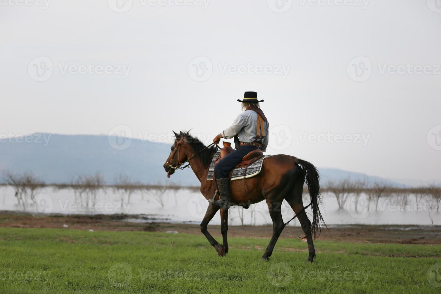 vaquero de silueta a caballo contra una hermosa puesta de sol, vaquero y caballo a primera luz, montaña, río y estilo de vida con fondo de luz natural foto