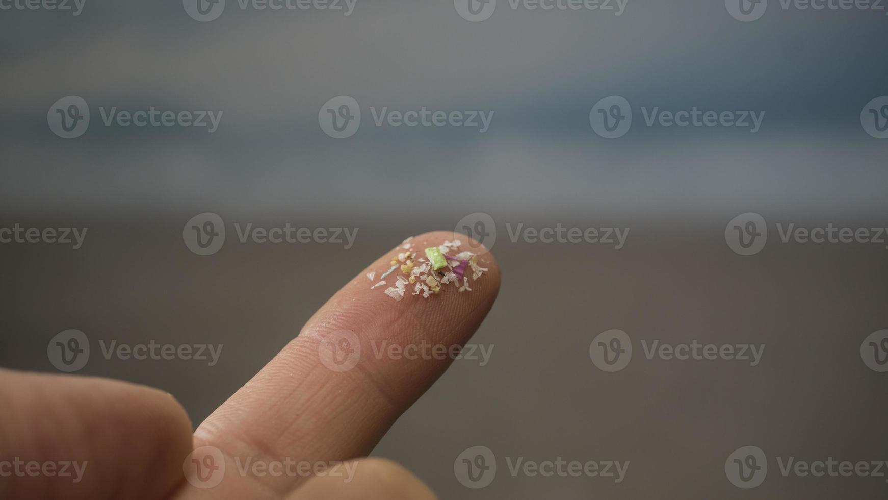 Close up side shot of microplastics on human fingers. Concept for water pollution and global warming.  Climate change idea. Soft focus on bunch of micro plastic that cannot be recycled. photo