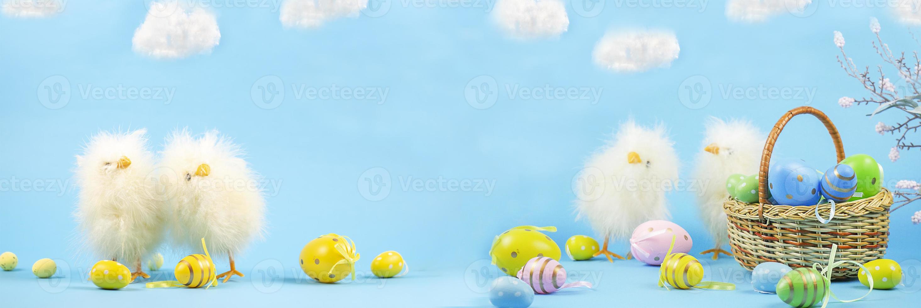 Easter composition with paschal eggs and chickens. Easter on a blue background. Basket with Easter eggs. Chick. Banner. copy space photo