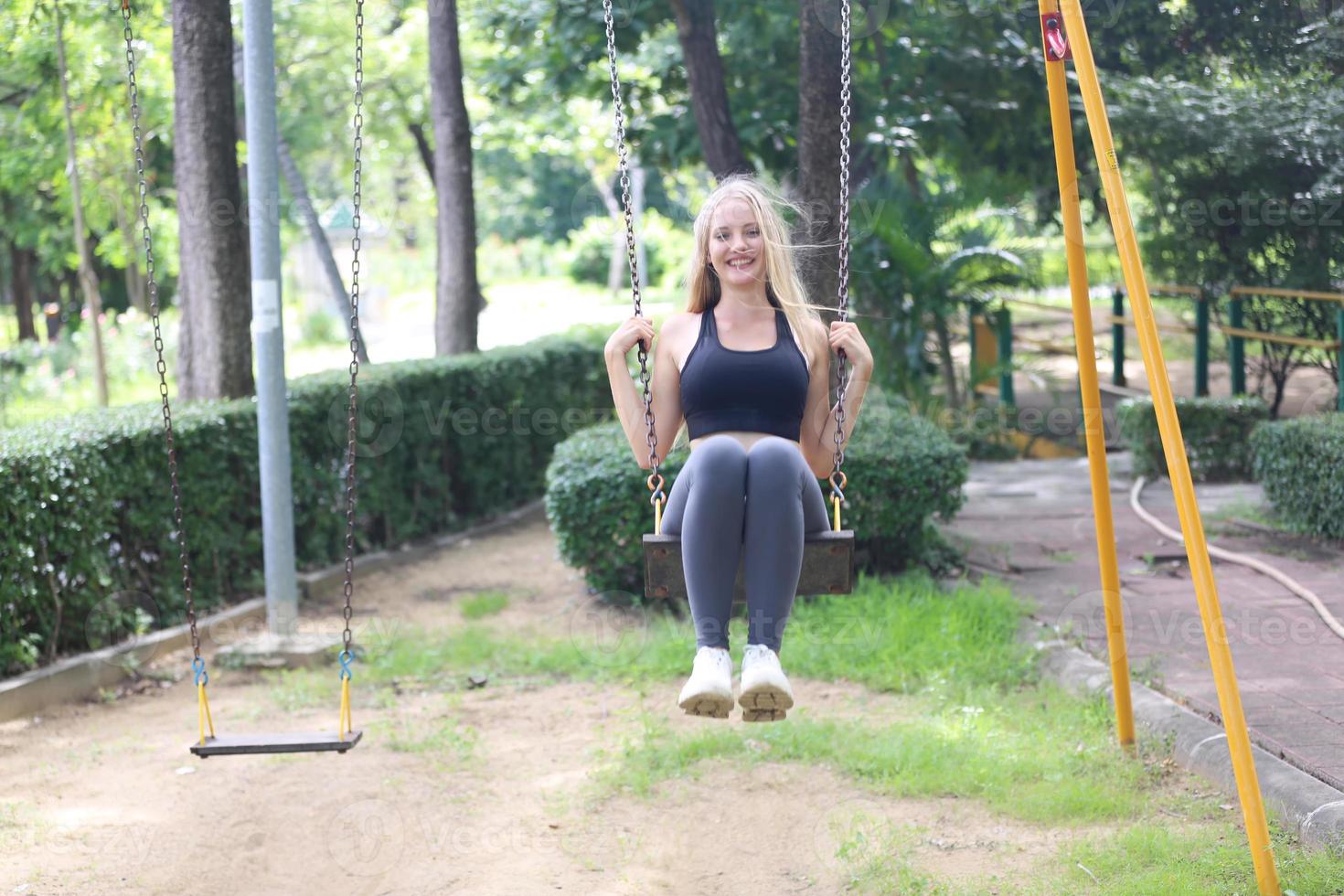 A beautiful woman wearing exercise clothes is playing and enjoying the nature in the garden during the day. photo