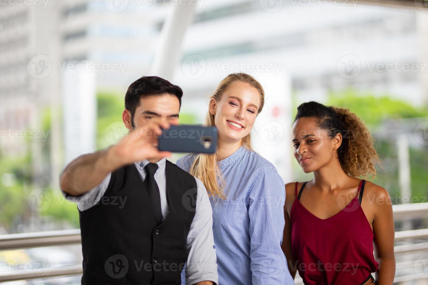 young business people take photo by mobile phone while walking on sidewalk at outside.