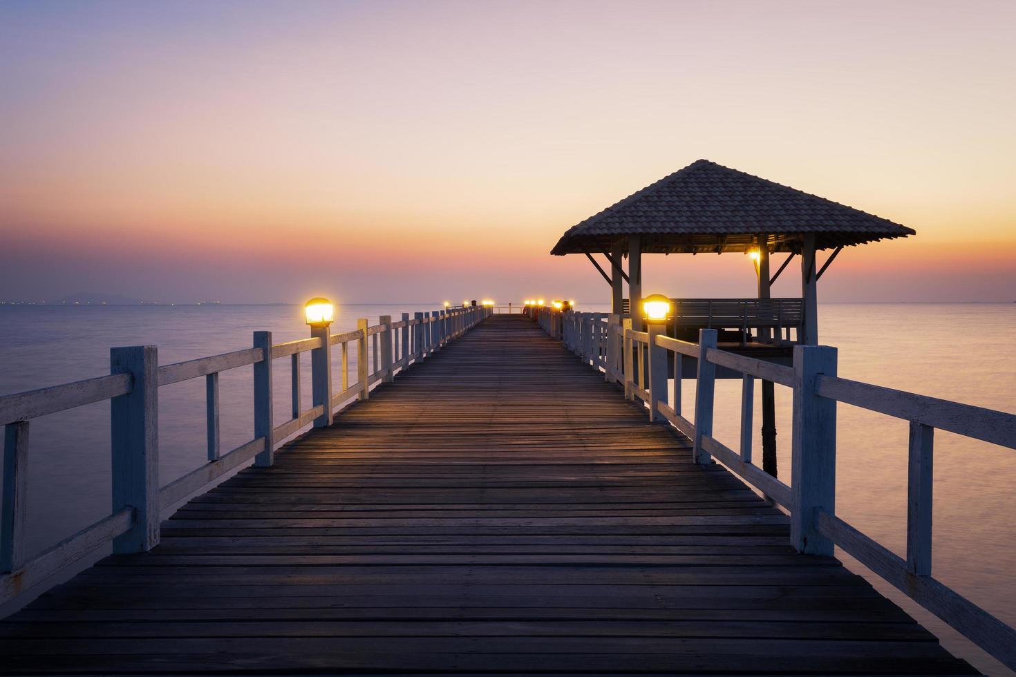 vista del puente de madera que se adentra en el mar al atardecer foto