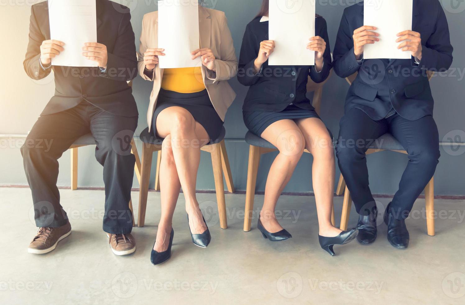 A group of businesspeople is sitting in a row in an office lobby photo