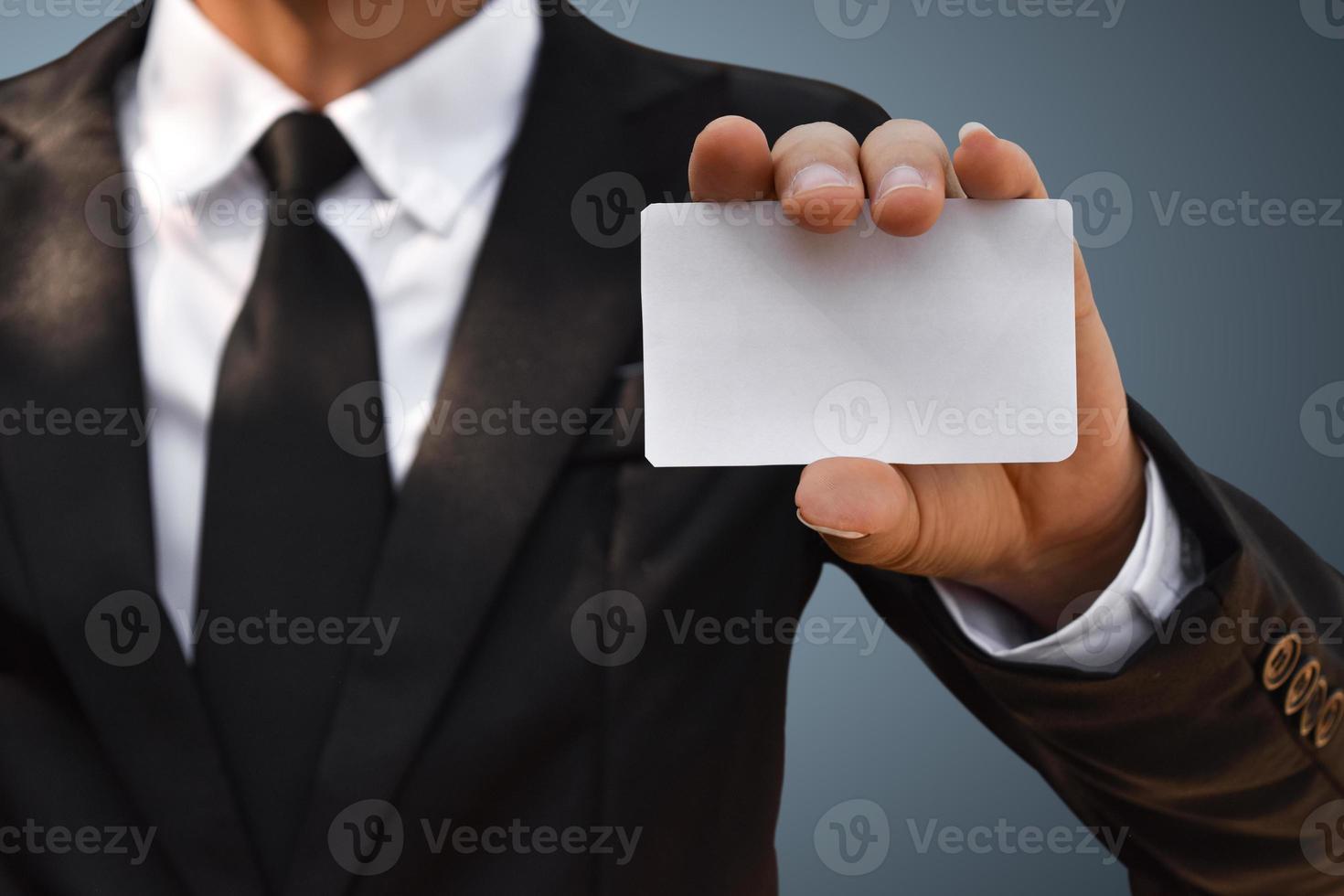 Closeup of businessman showing white piece of paper in black suit. Idea for business credit card or visiting card. photo
