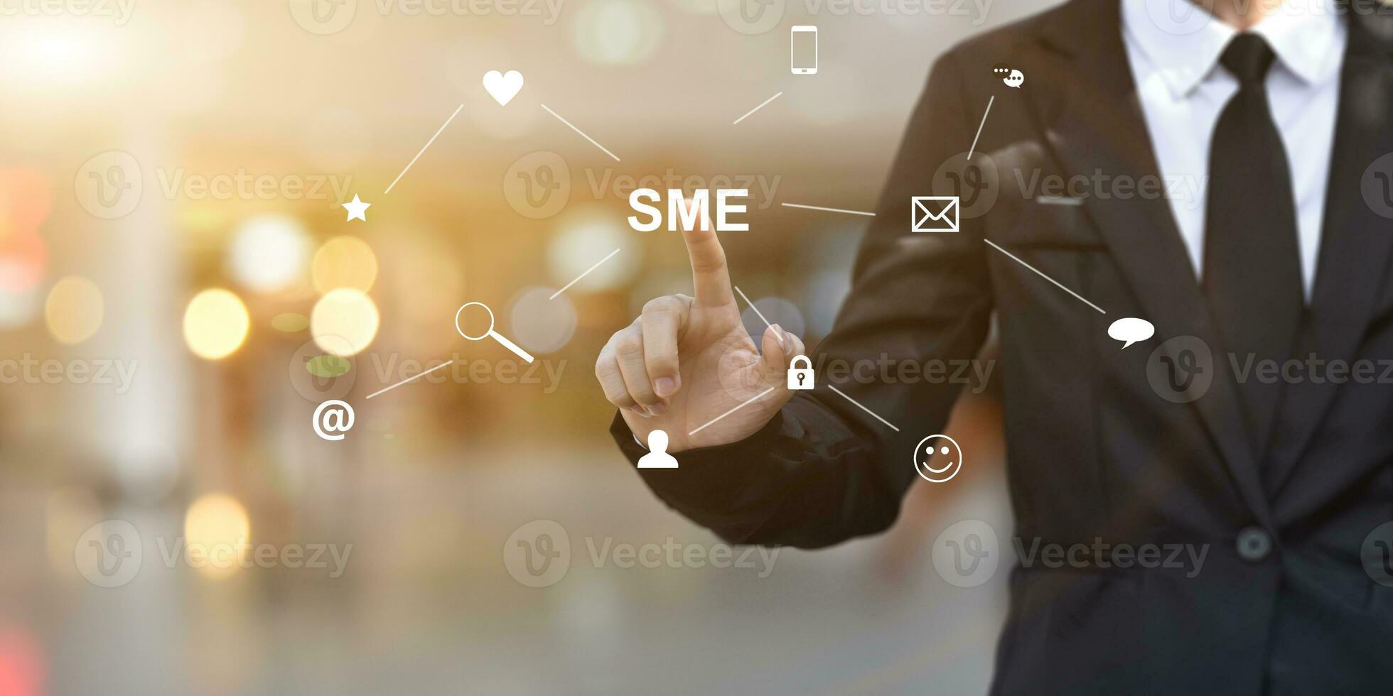Businessman hand pressing button SME icon on virtual screen. Idea for Small and medium-sized enterprises business. photo