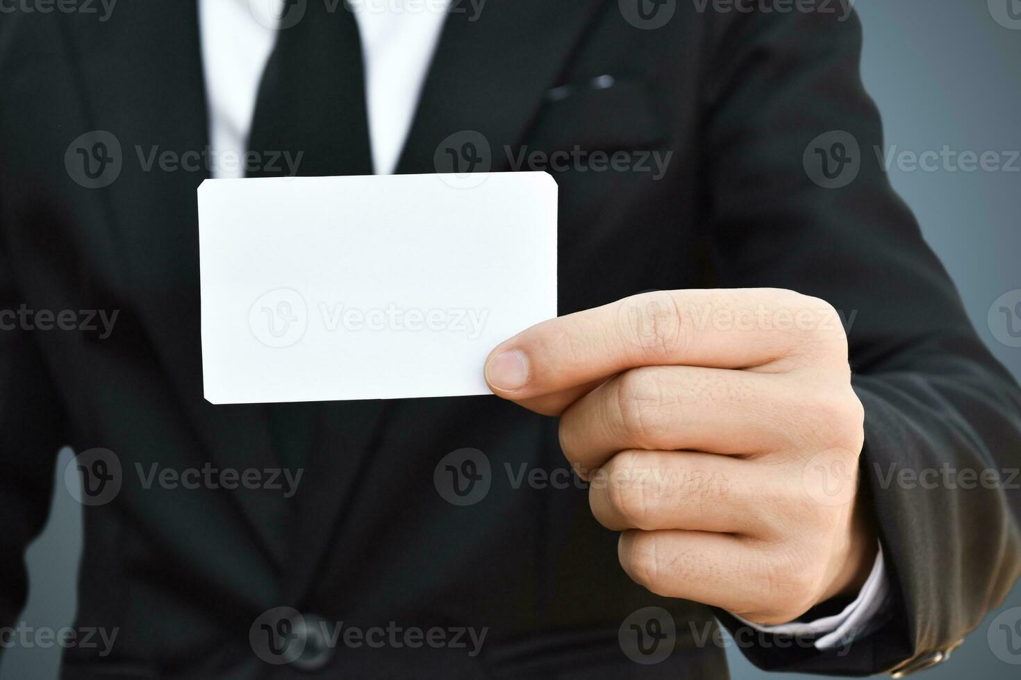 Closeup of businessman showing white piece of paper in black suit. Idea for business credit card or visiting card. photo