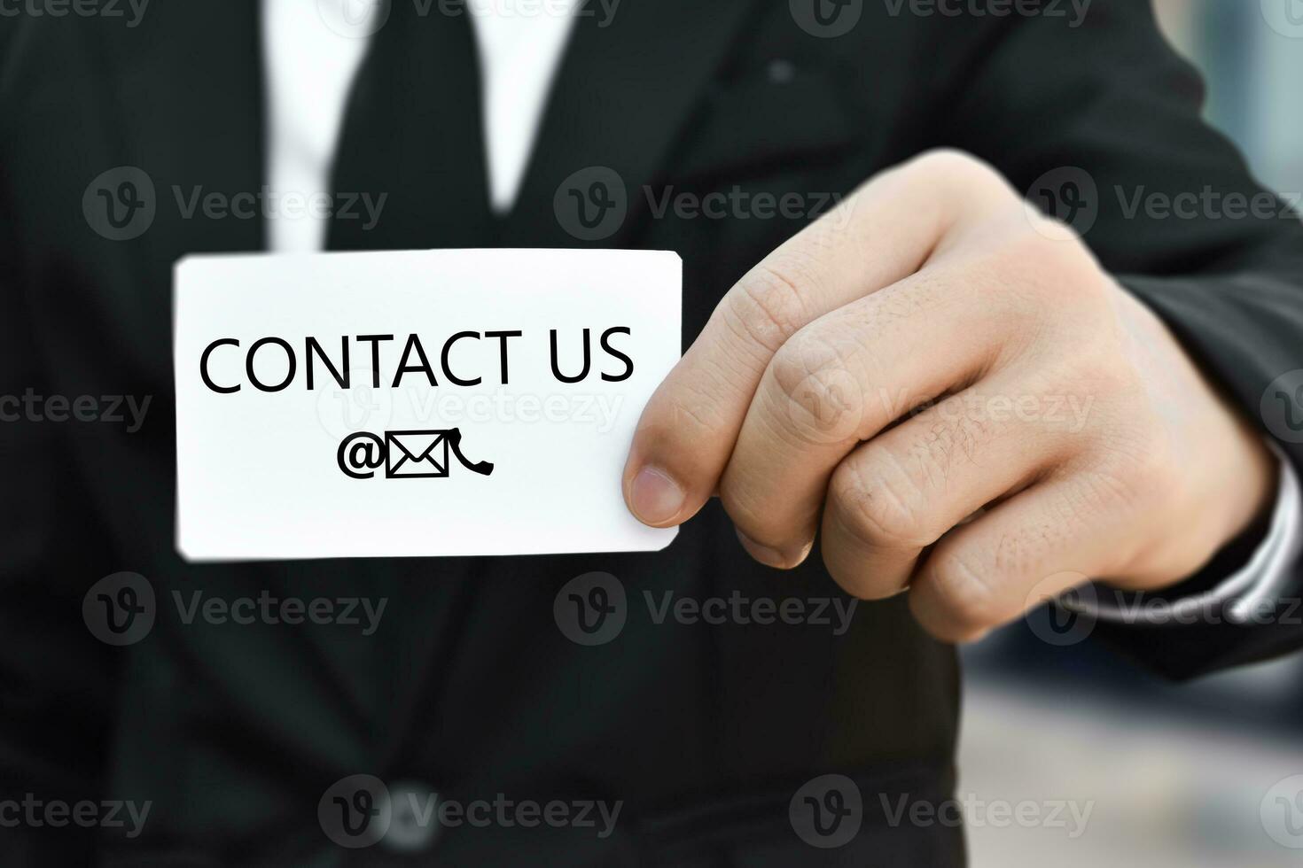 Businessman hand holding business card with the message contact us. Idea for customer support hotline people connect photo