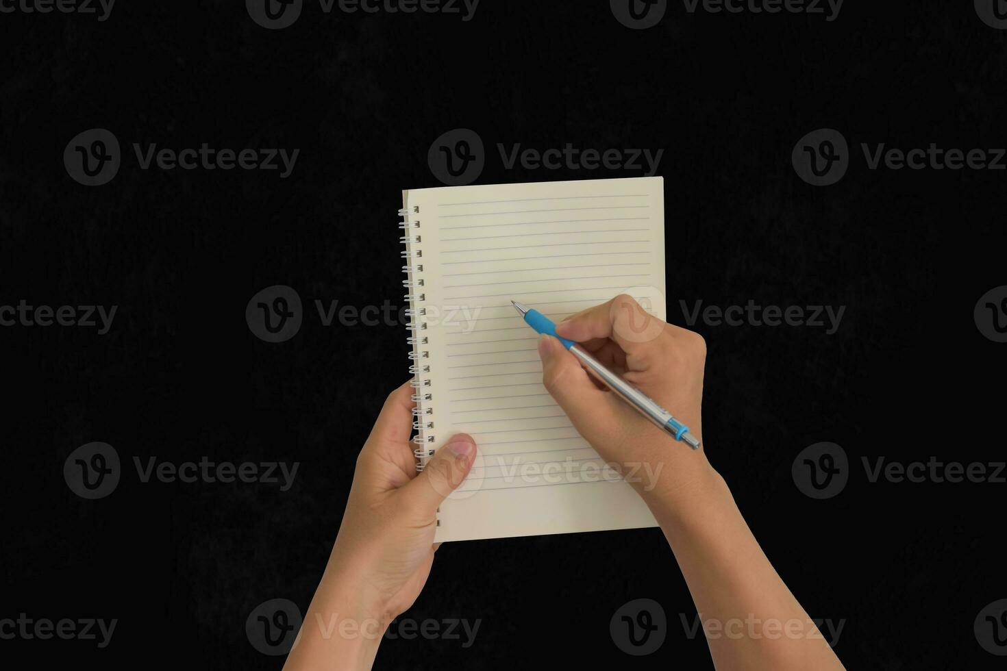 Hand holding pen, with a blank notes over blackboard background. Design concept photo