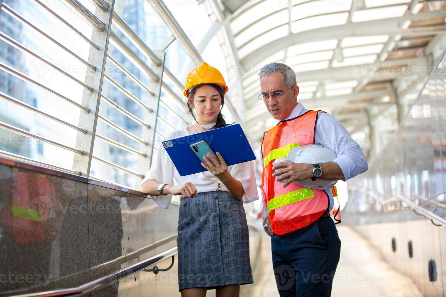 The engineer and business woman checking on clipboard at construction site building. The concept of engineering, construction, city life and future. photo