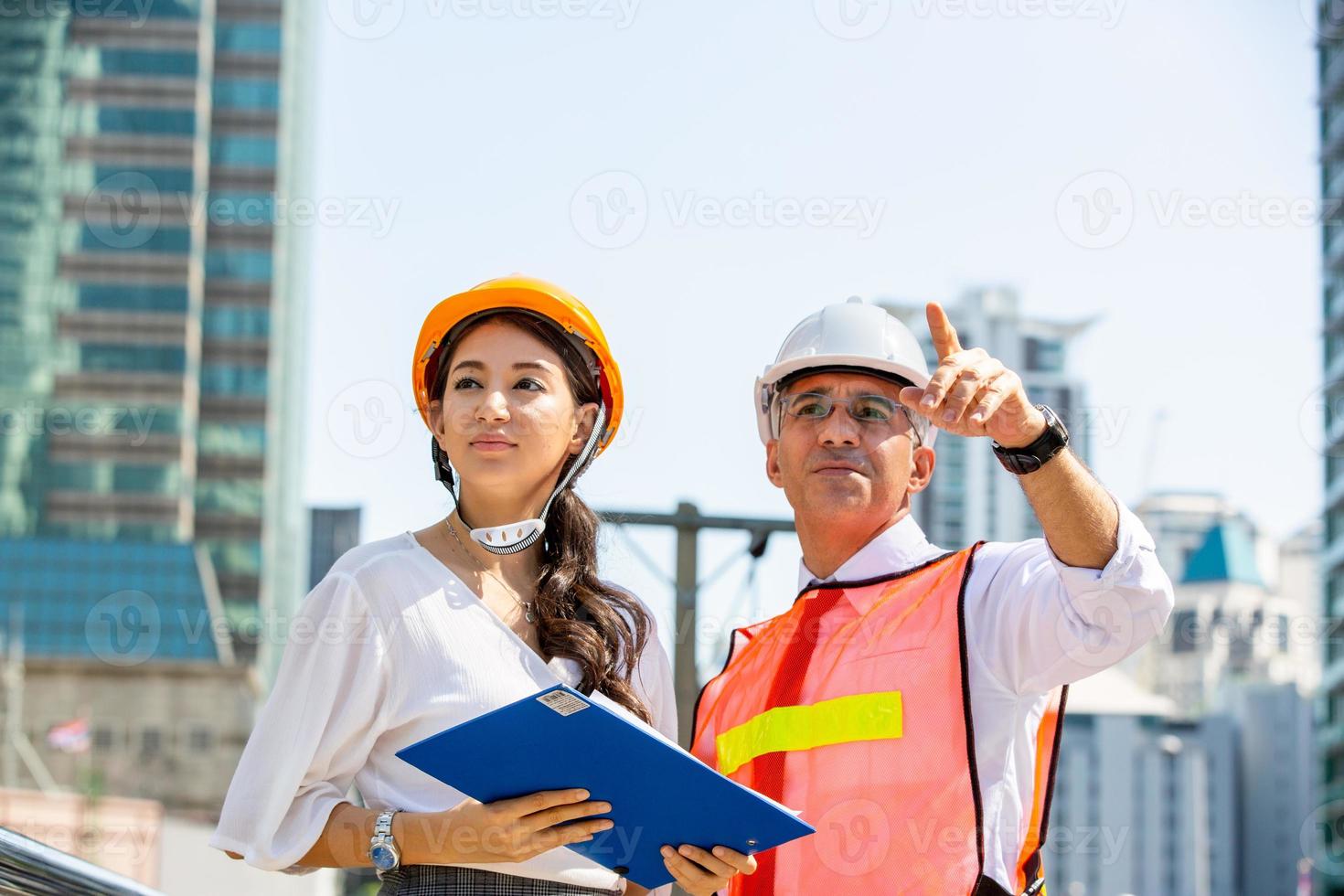 el ingeniero y la mujer de negocios revisando el portapapeles en el edificio del sitio de construcción. el concepto de ingeniería, construcción, vida urbana y futuro. foto