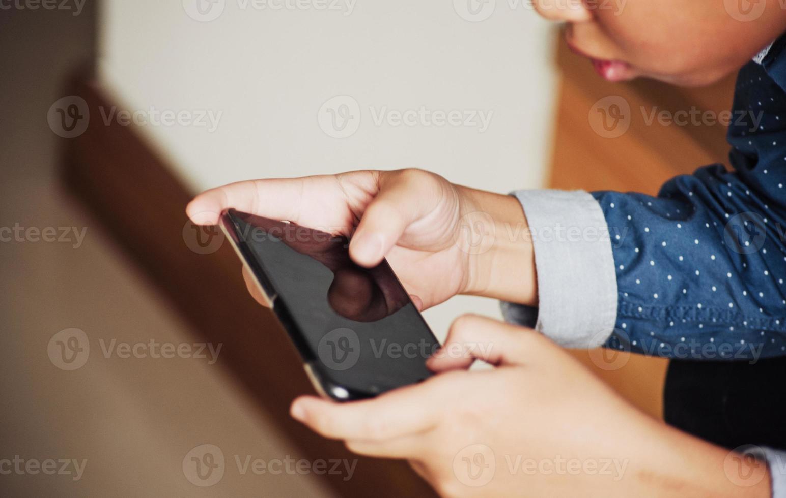 niño jugando juegos en teléfonos inteligentes, niño mano sosteniendo un teléfono inteligente foto