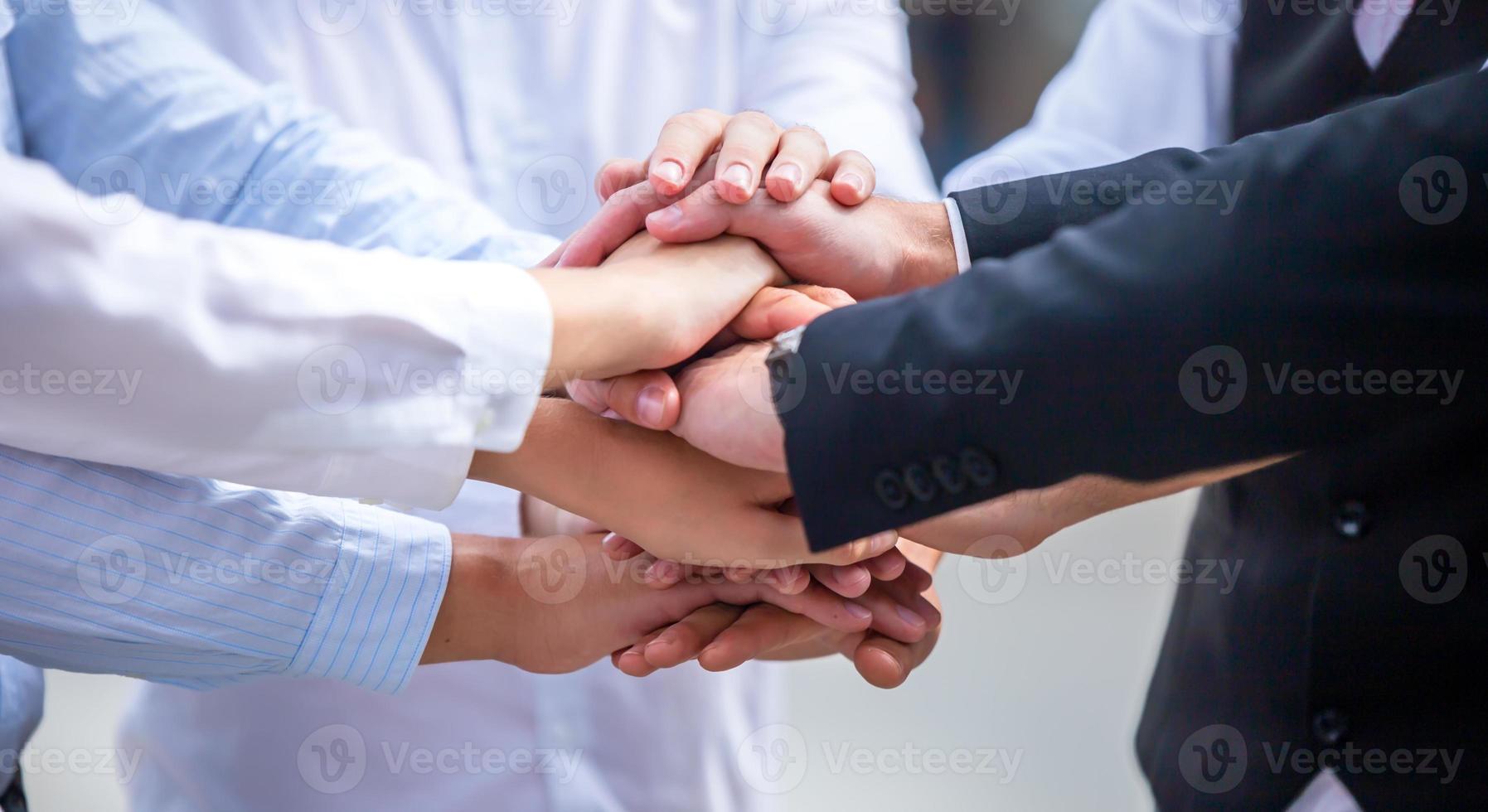 Stack of hands. Unity and teamwork concept. Close up top view of young business people putting their hands together photo