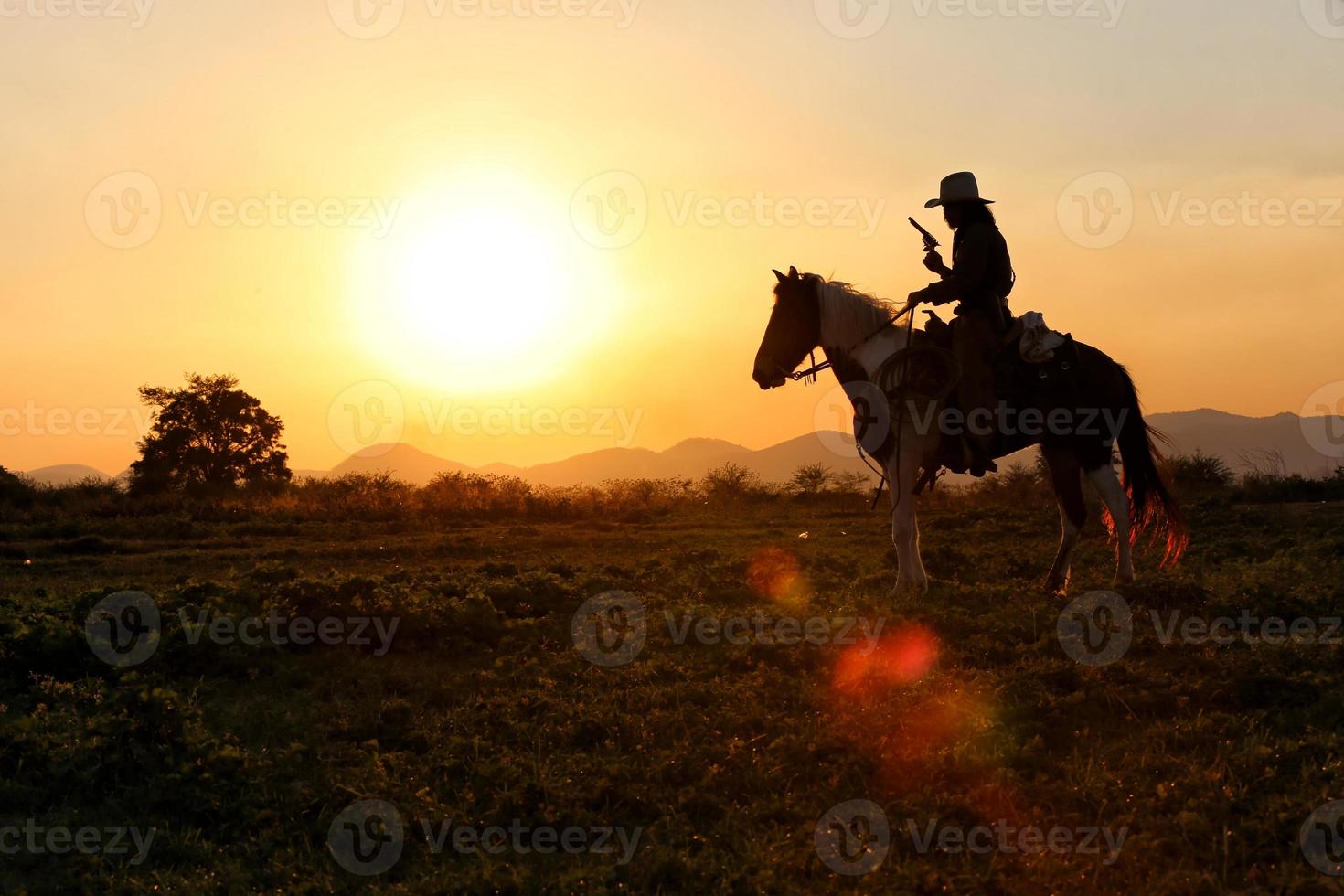 Cowboy on horseback against a beautiful sunset, cowboy and horse at first light, mountain, river and lifestyle with natural light background photo