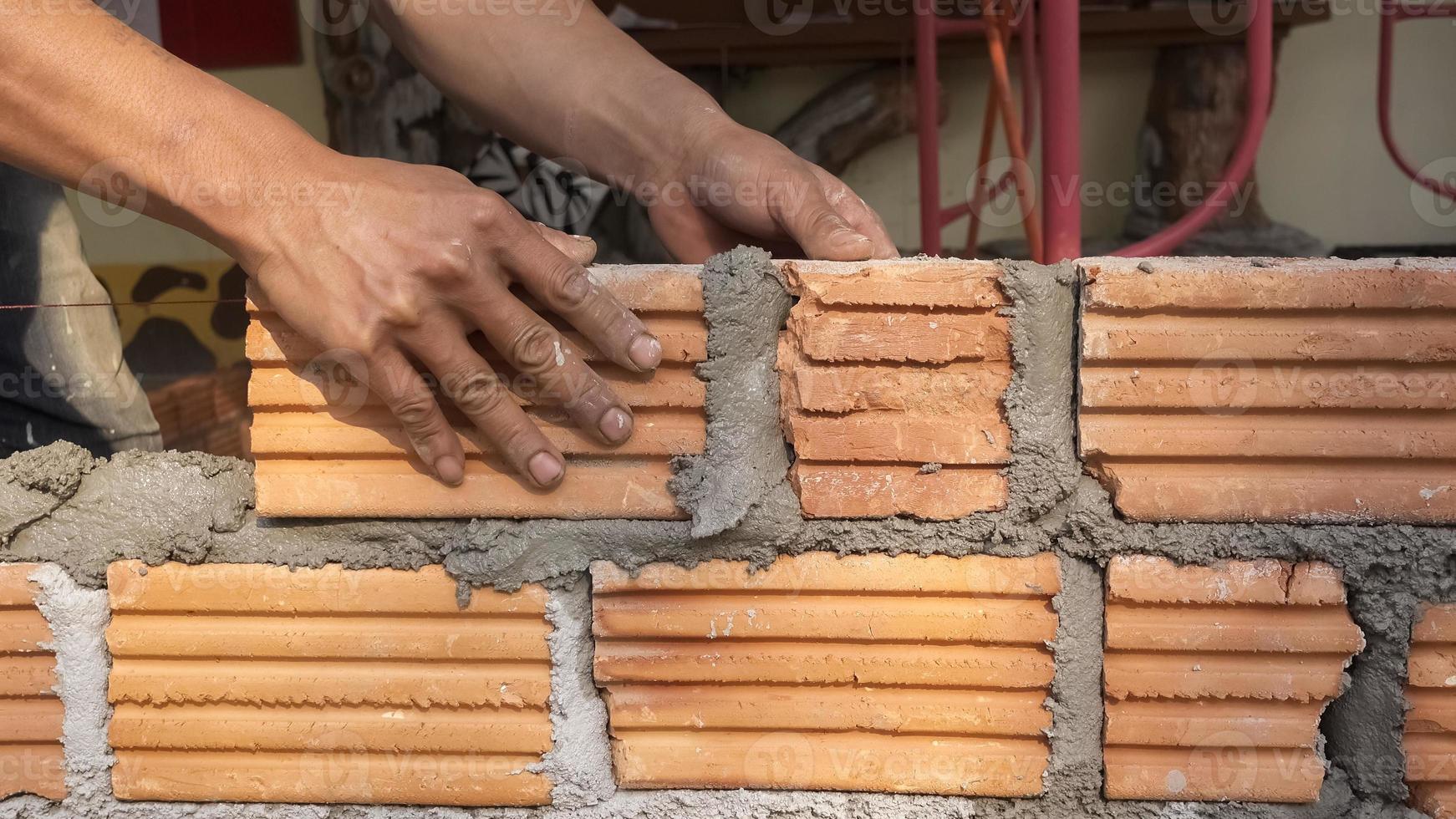 Bricklayer worker installing brick masonry on exterior wall photo