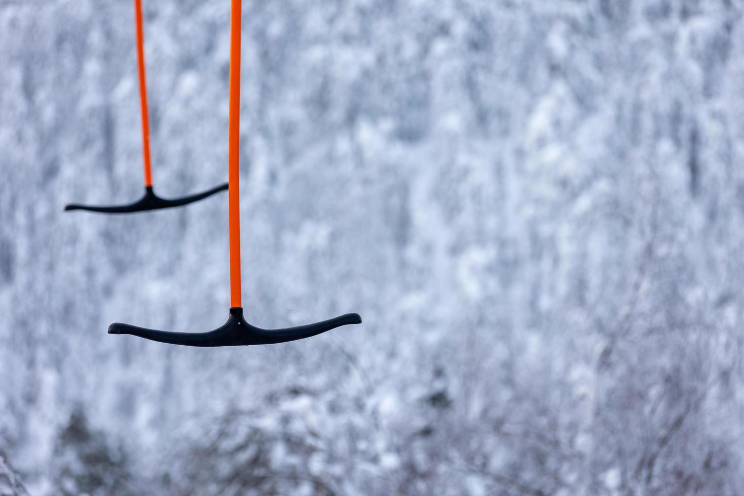 Two t-bar skiing lift poles against blurred snow forest. photo