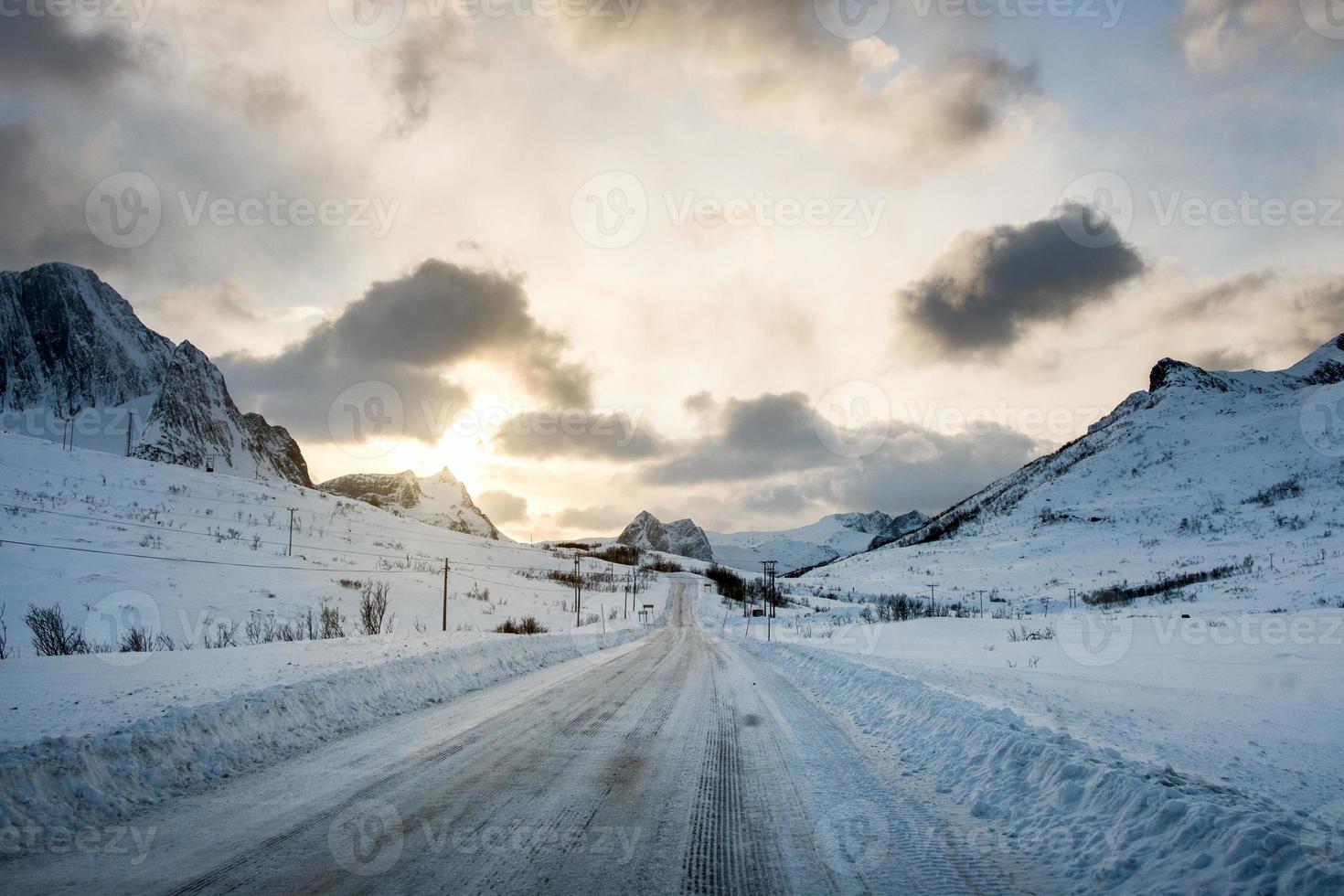 Dirty snow road with sunlight on mountains photo