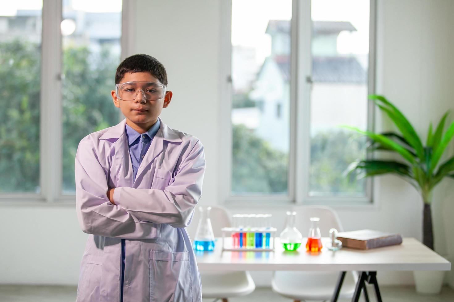 niño pequeño mezcla productos químicos en vasos de precipitados. niños de pie con tubo de ensayo en el laboratorio de la escuela. foto