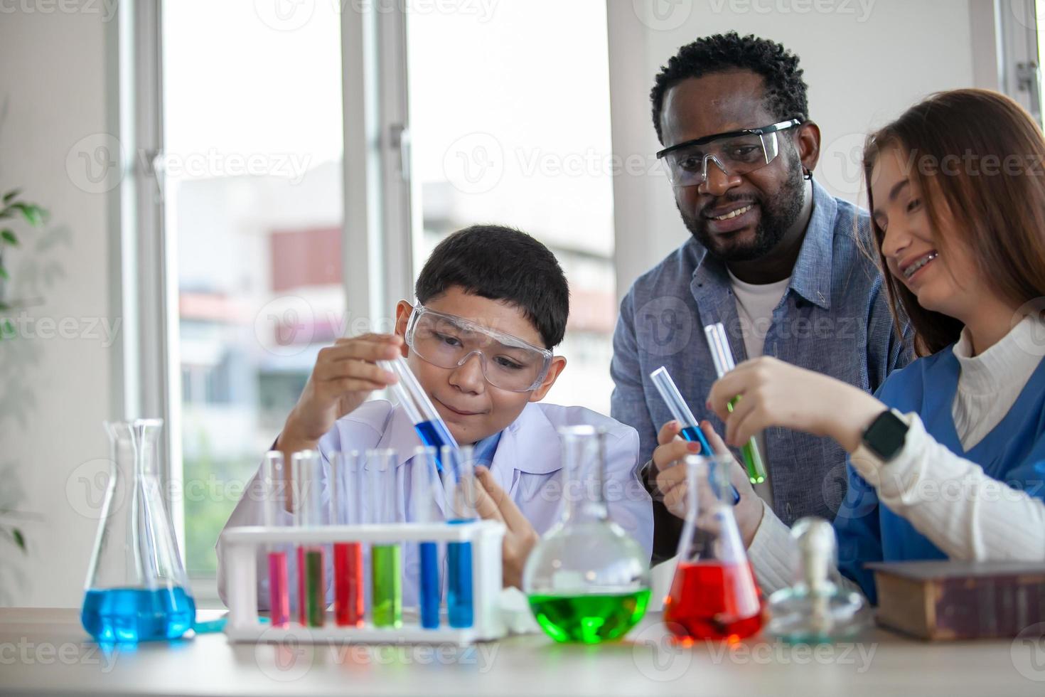 Students mixes chemicals in beakers. enthusiastic teacher explains chemistry to children, chemistry student showing new experiment to teacher science class photo