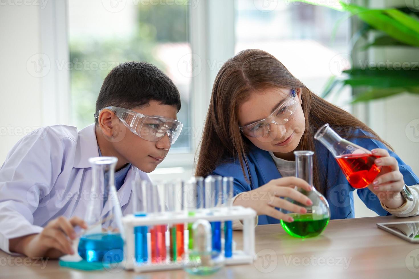 los estudiantes mezclan productos químicos en vasos de precipitados. estudiante de química mezcla productos químicos en la clase de ciencias foto