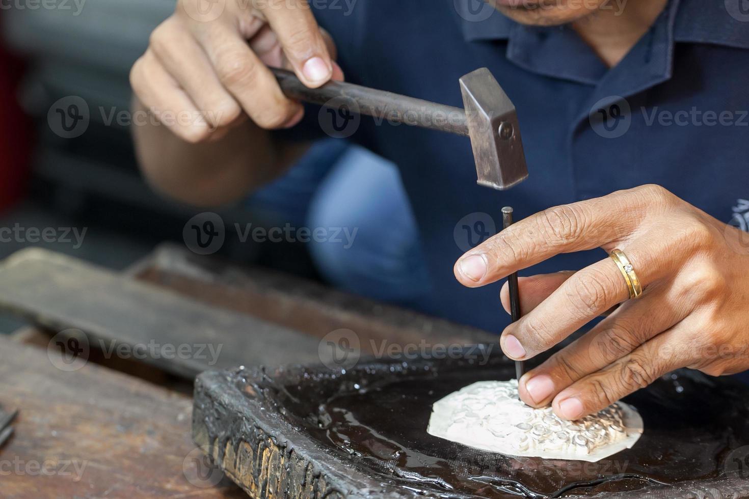 Silversmith using hammers and steel engraved  pattern on silver plate for accessory handmade photo