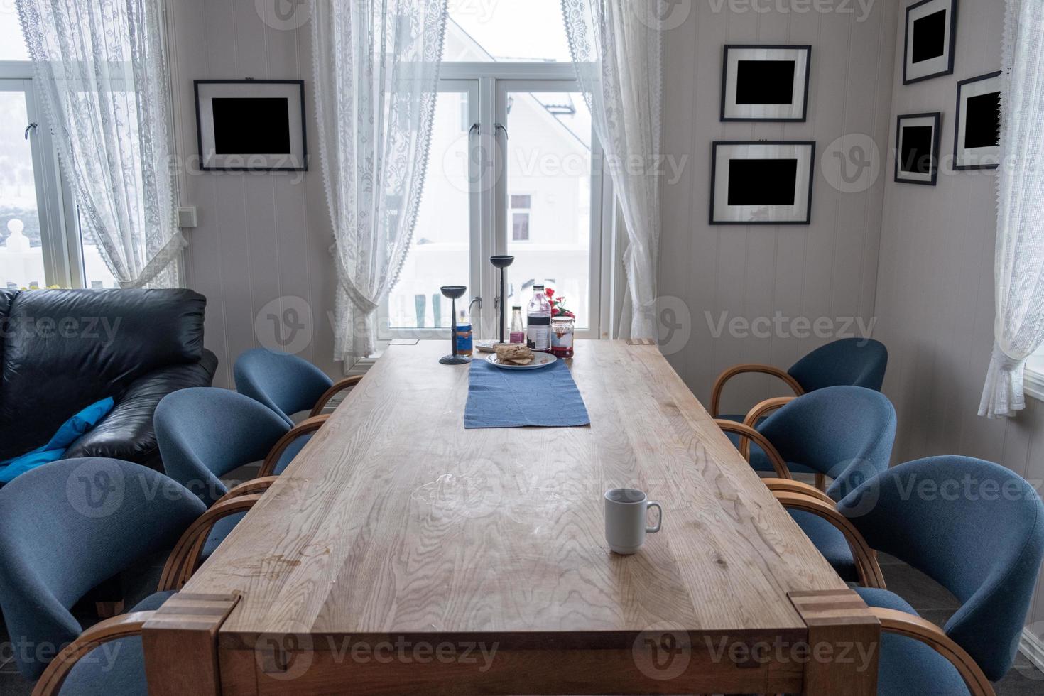 Interior wooden dining table with chairs and blank picture frame on winter photo