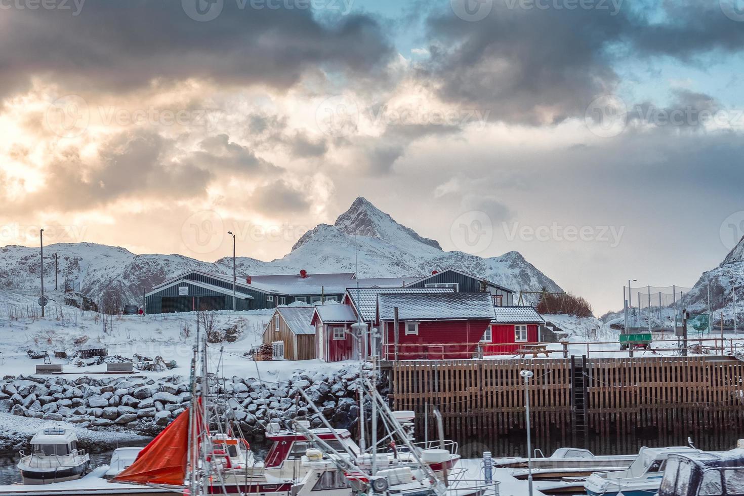 pueblo escandinavo con barco de pesca y montaña nevada en la costa foto