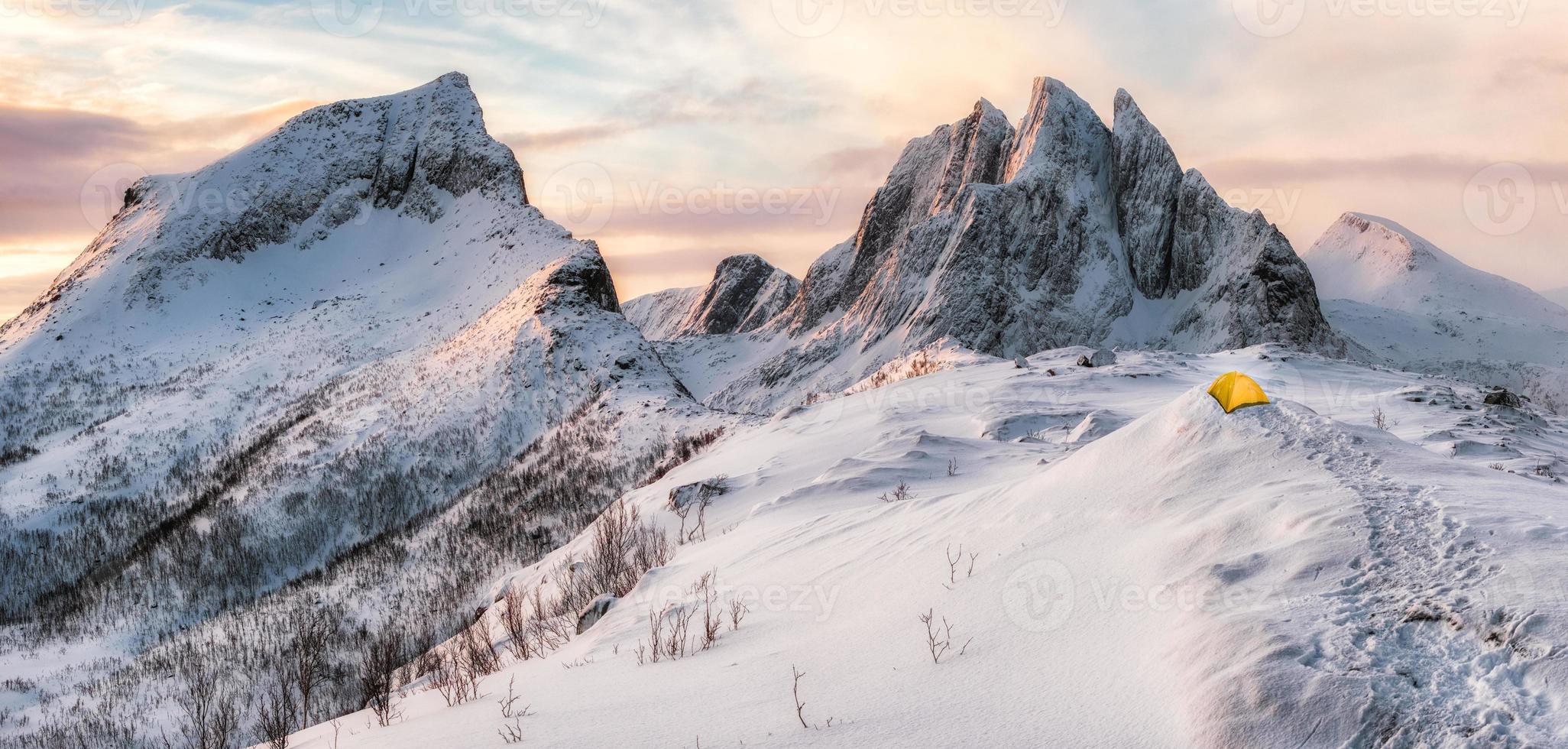 Panorama of Steep peak mountains with covered snow and yellow tent photo