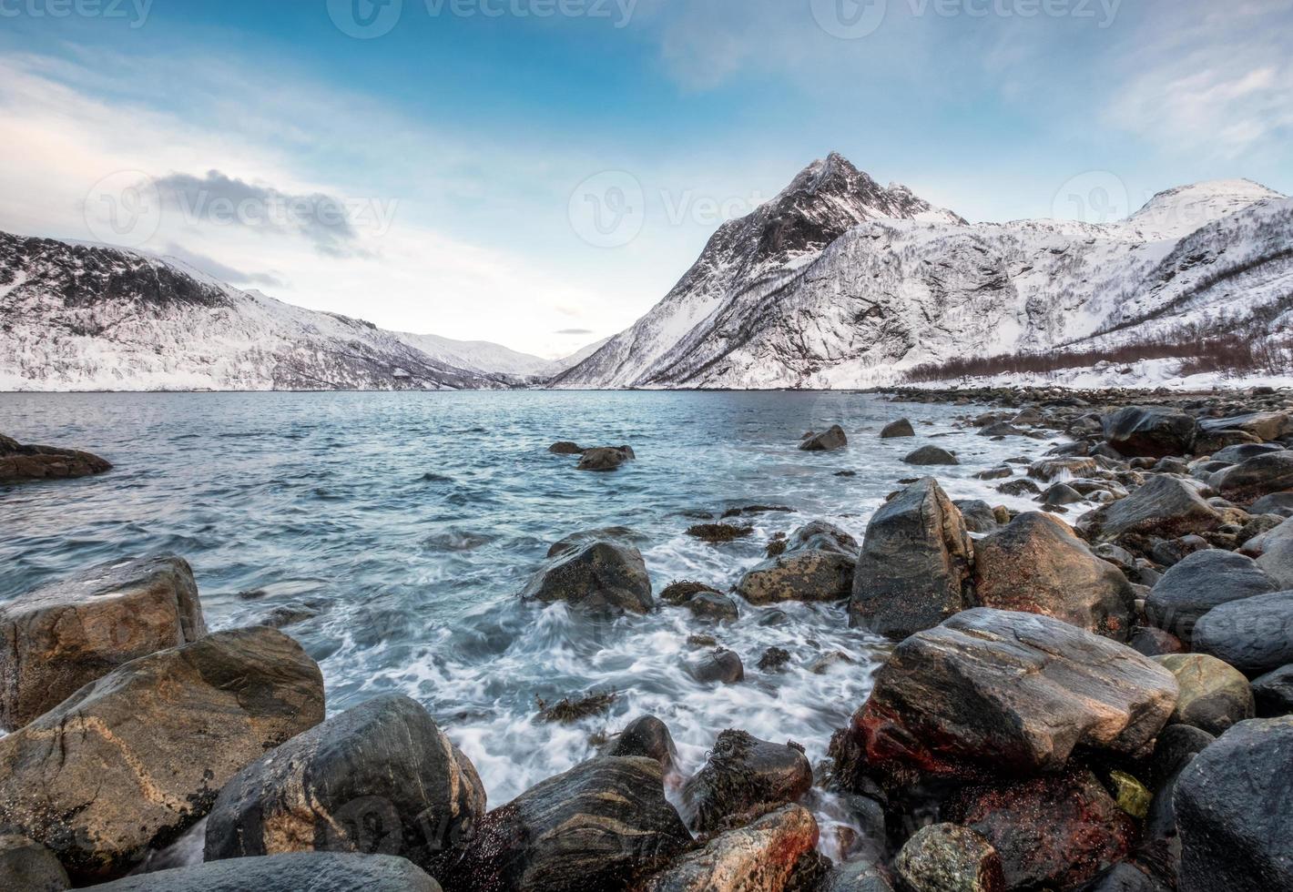 Seascape wave hitting rocks with mountains on arctic coastline photo