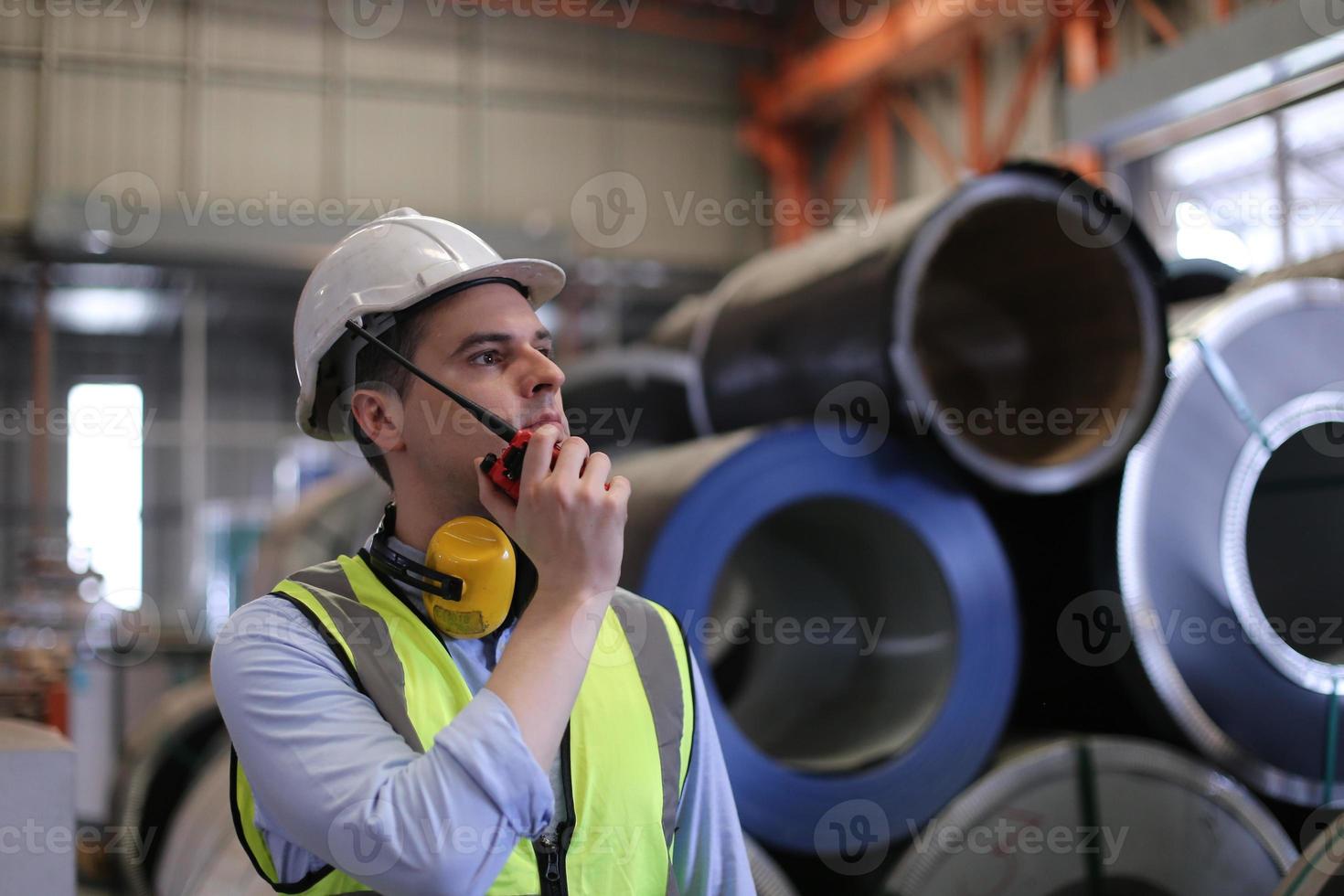 ingeniero industrial masculino con casco de seguridad mientras está de pie en una fábrica industrial pesada. el mantenimiento que busca trabajar en maquinaria industrial y verificar la configuración del sistema de seguridad en fábrica. foto
