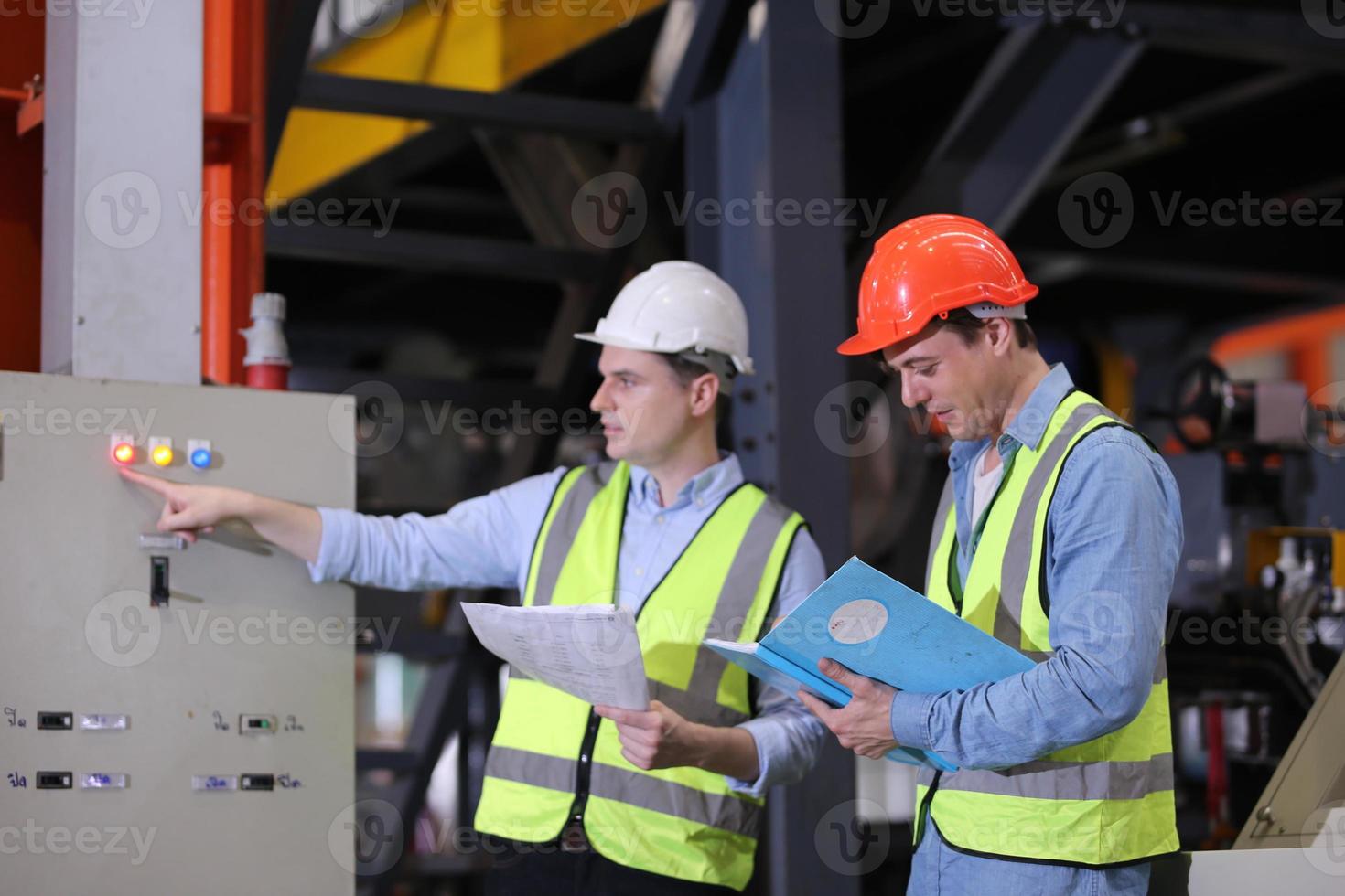 Men industrial engineer wearing a safety helmet while standing in a heavy industrial factory. The Maintenance looking of working at industrial machinery and check security system setup in factory. photo