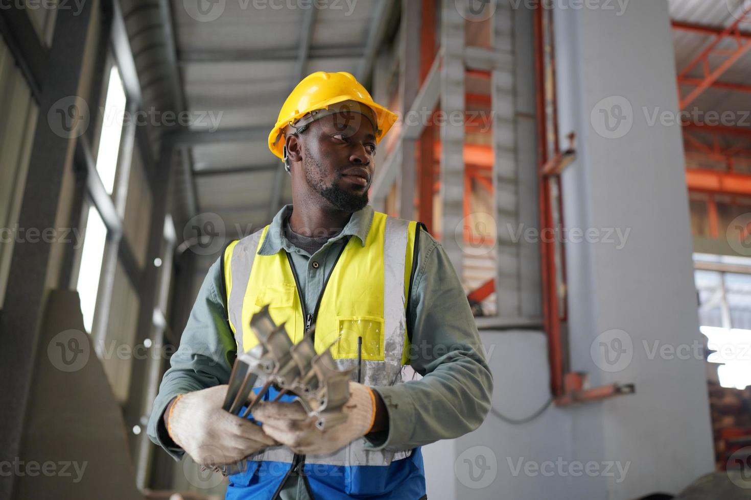 ingeniero industrial masculino con casco de seguridad mientras está de pie en una fábrica industrial pesada. el mantenimiento que busca trabajar en maquinaria industrial y verificar la configuración del sistema de seguridad en fábrica. foto