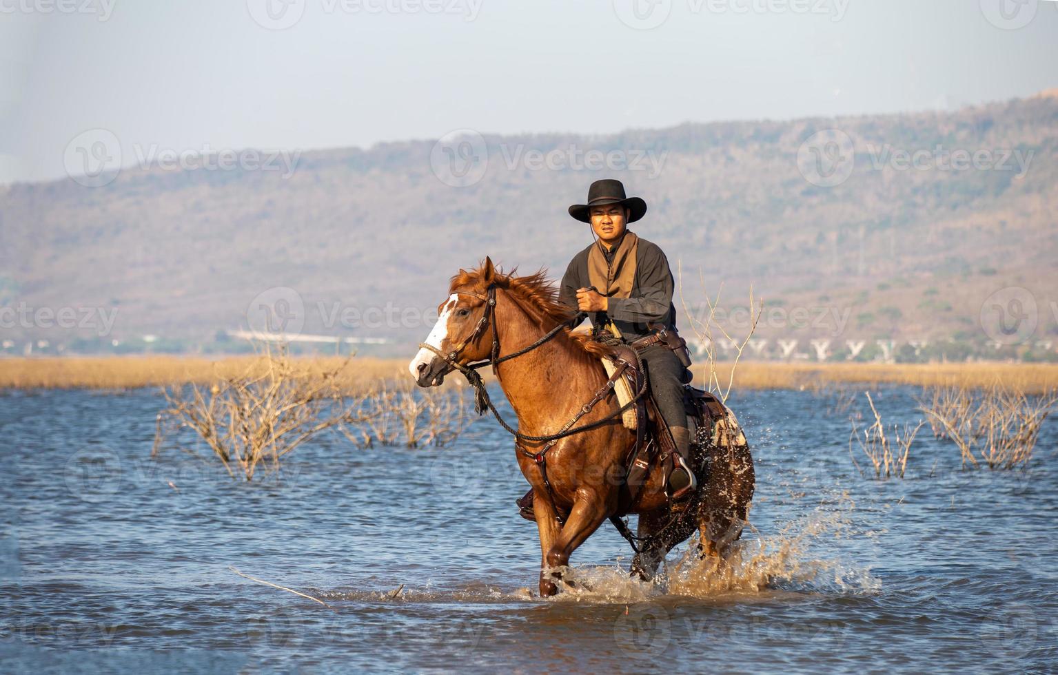 vaquero a caballo contra una hermosa puesta de sol, vaquero y caballo a primera luz, montaña, río y estilo de vida con fondo de luz natural foto