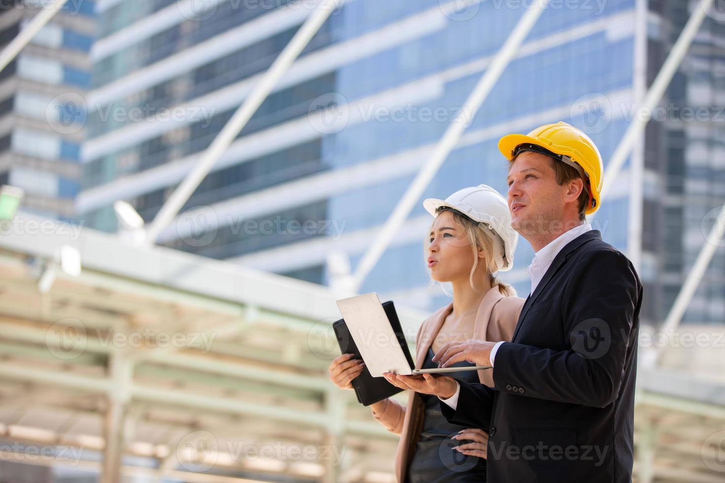 el ingeniero y la mujer de negocios revisando el portapapeles en el edificio del sitio de construcción. el concepto de ingeniería, construcción, vida urbana y futuro. foto