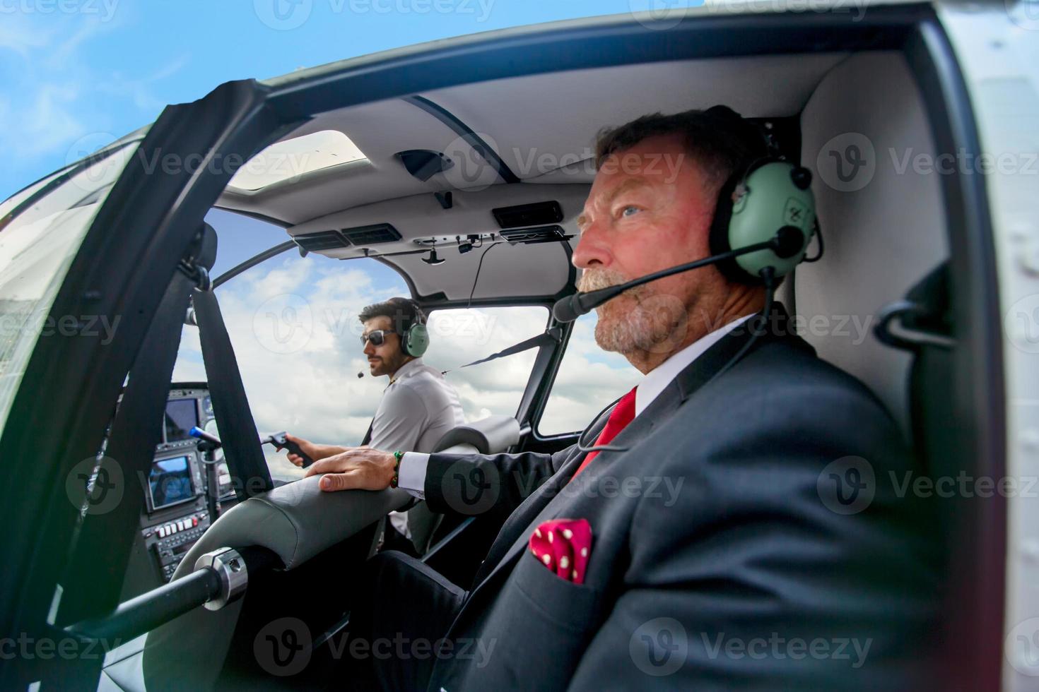 Business people traveling by helicopter , Shot of a mature businessman using a headset while traveling in a helicopter photo