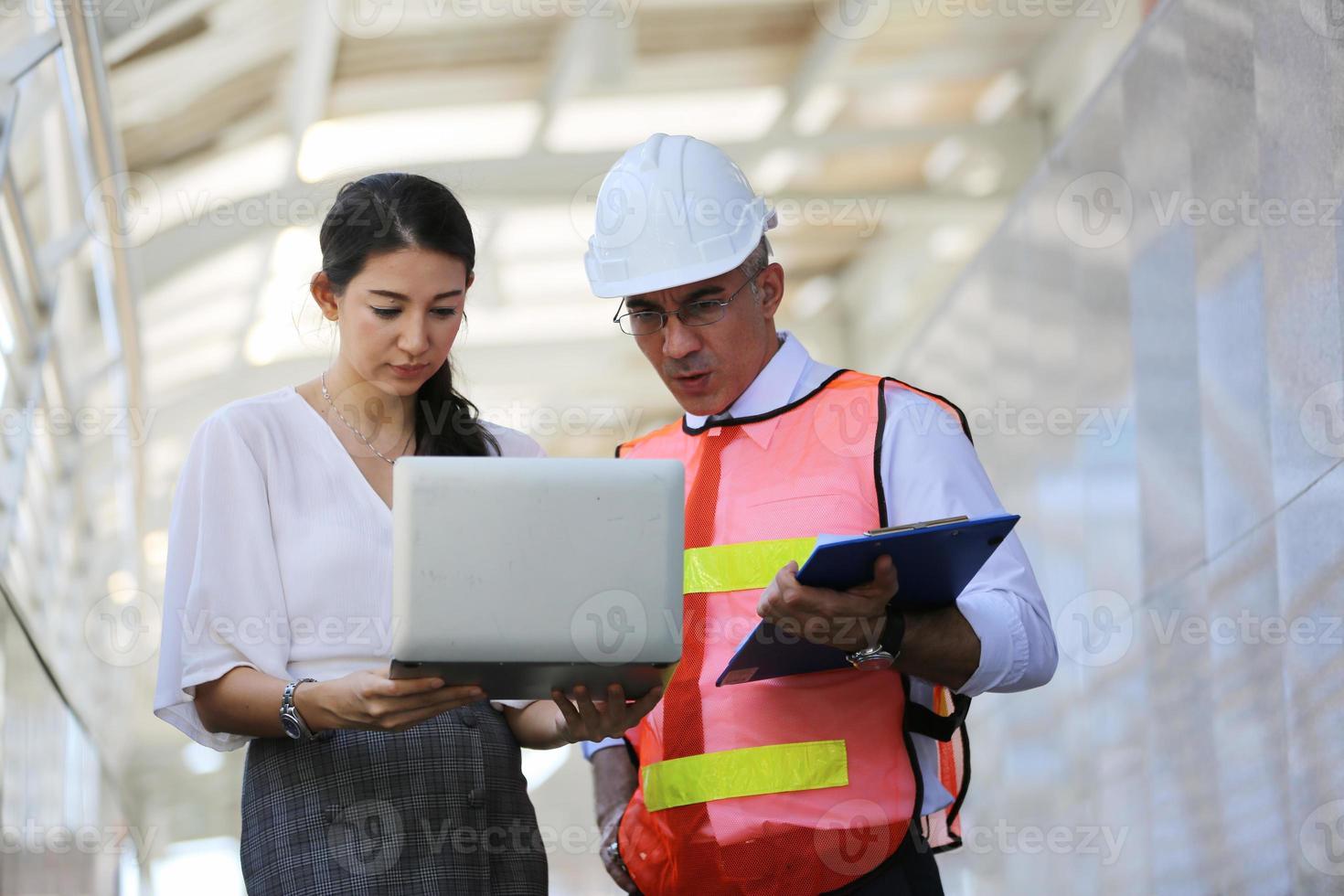 el ingeniero y la mujer de negocios revisando el portapapeles en el edificio del sitio de construcción. el concepto de ingeniería, construcción, vida urbana y futuro. foto