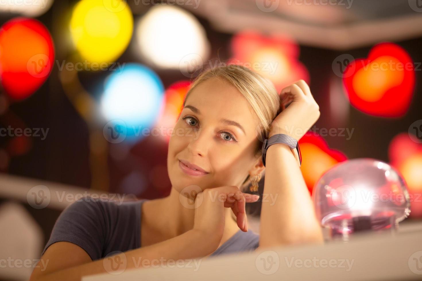 retrato de mujer sonriendo de pie contra la colorida luz bokeh foto