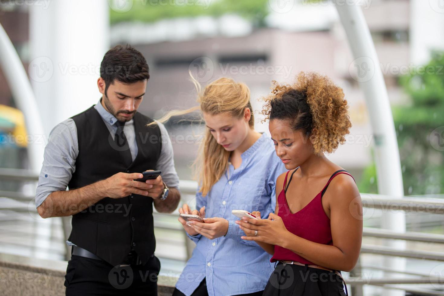 young business people texting on mobile phone while walking on sidewalk at outside. photo