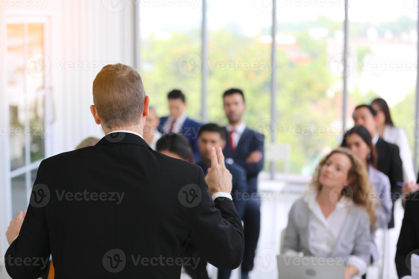 Speaker giving presentation in hall. Audience or conference hall. Rear view of unrecognized participants in audience. Scientific conference event, training photo