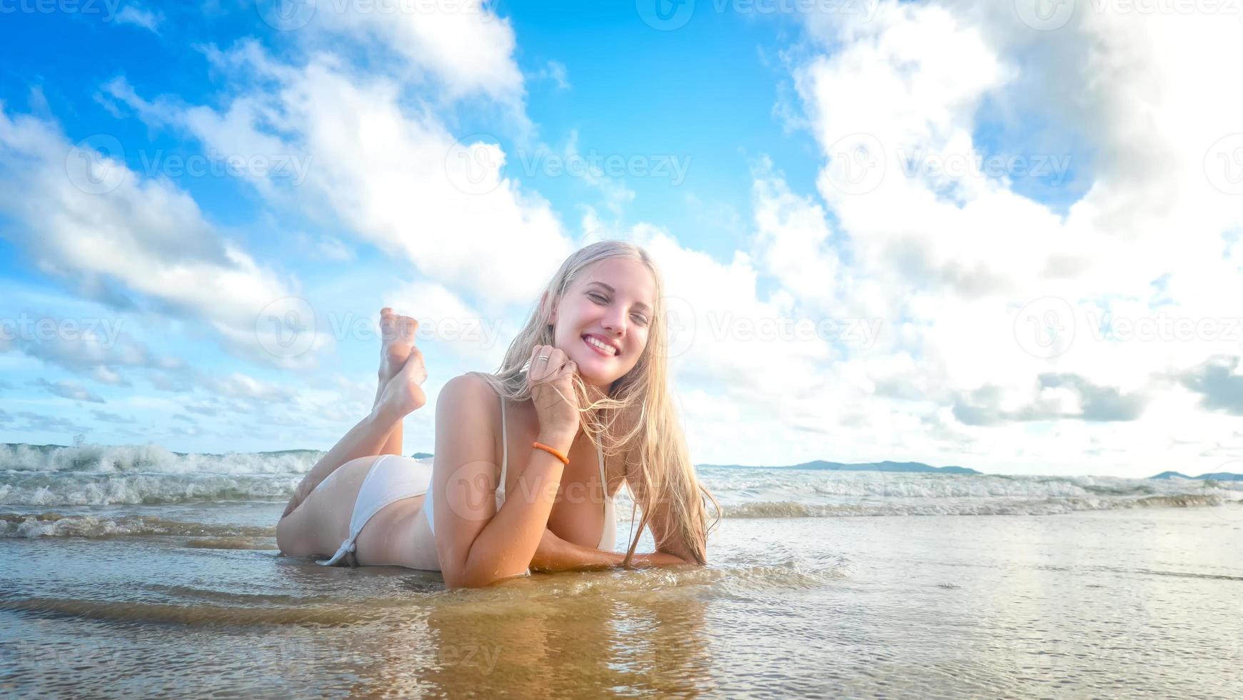 retrato de una hermosa mujer rubia disfruta de su verano en la playa. foto